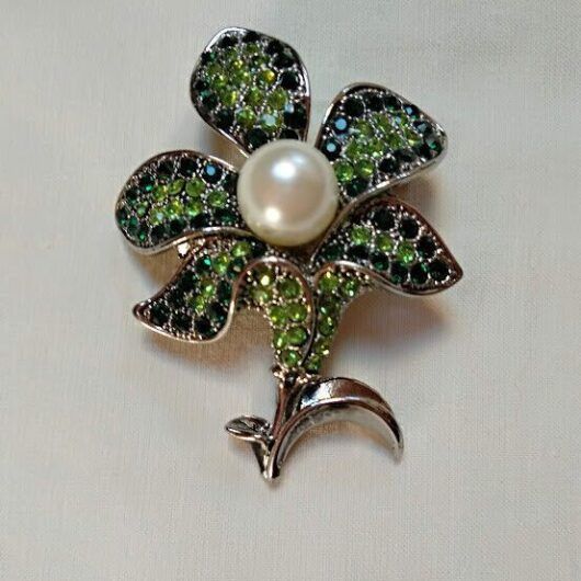 Broche bisuteria plateado en forma de flor cuajado piedras verdes y perla .Nuevo