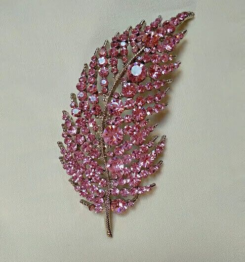 Broche bisuteria plateado en forma de hoja cuajado de piedras color rosa.Nuevo
