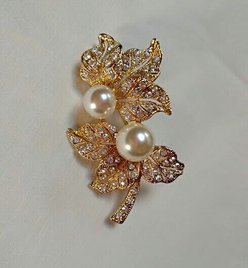 Broche bisuteria dorado con forma de hojas similes blancos y perlas.Nuevo